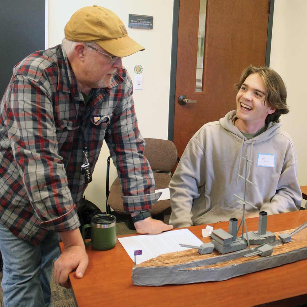 A student discusses their final project with Dennis Johnson