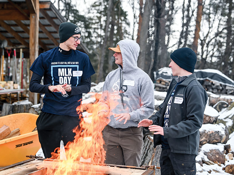group of students gathered around a fire in the cold