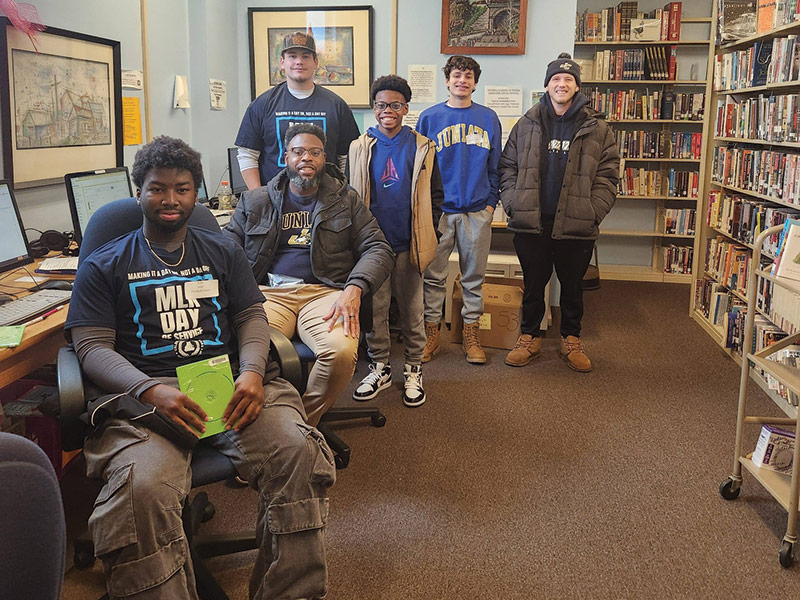Eric Jallah ’27 was part of a group of volunteers guided by Derek James, dean of access, opportunity, and leadership development, serving the Mount Union Community Library.