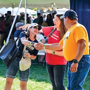 photo of alums shaking hands at the jamboree on the quad