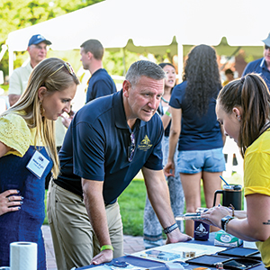 Madison (Troha) Speck ’20 g’21 and President James A. Troha participate in an interactive stamping activity organized by Aubrey Zegstroo, graphic designer.